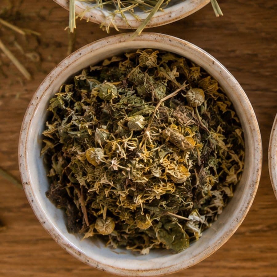 Schale mit getrockneten Kräutern und Kamillenblüten